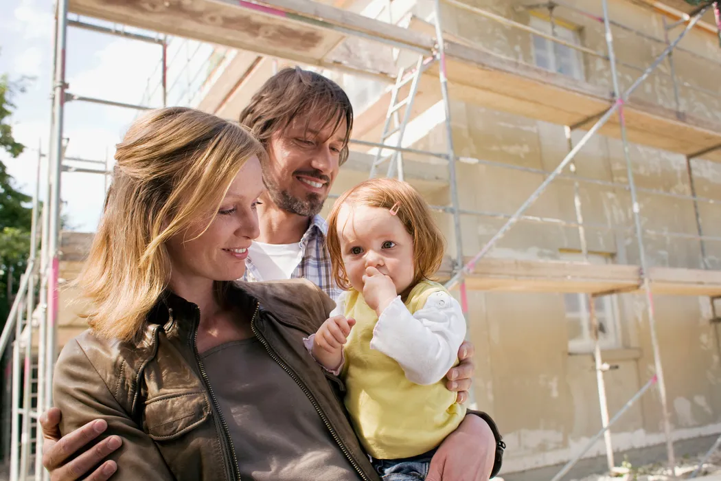 Risikolebensversicherung: Familie mit Rohbau eines neuen Hauses