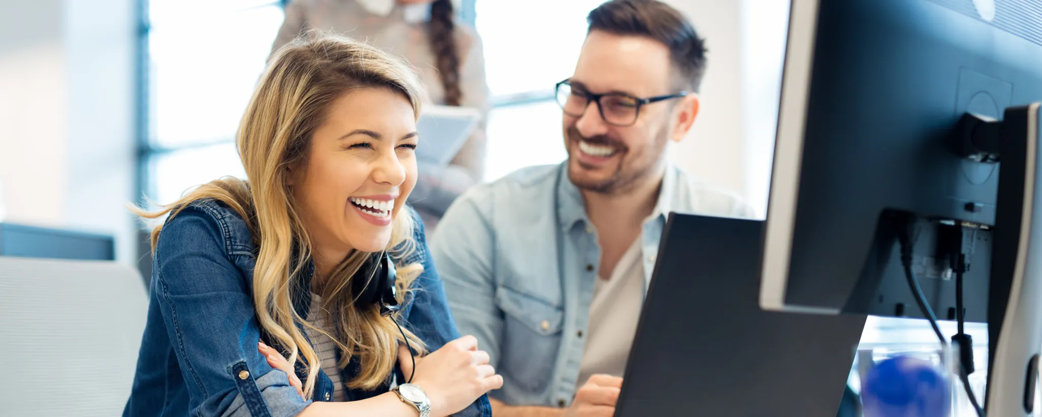 In einem modernen Büro in Deutschland arbeiten zwei Personen konzentriert an einem Computer. Sie diskutieren über Ausbildungsberufe und analysieren Informationen auf dem Bildschirm.