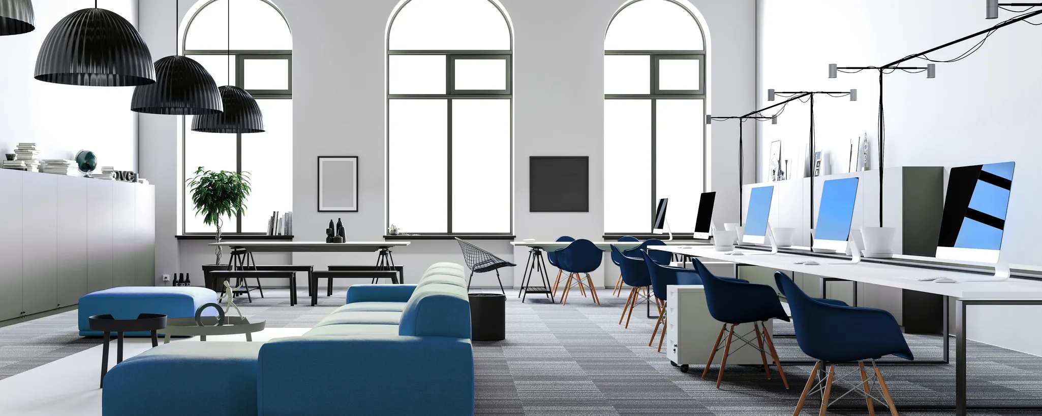 Der moderne Workspace zeigt eine stilvolle Einrichtung mit blauen Stühlen und Computern, die den Anforderungen verschiedener Generationen im Arbeitsleben gerecht werden. Große Fenster sorgen für viel Tageslicht.