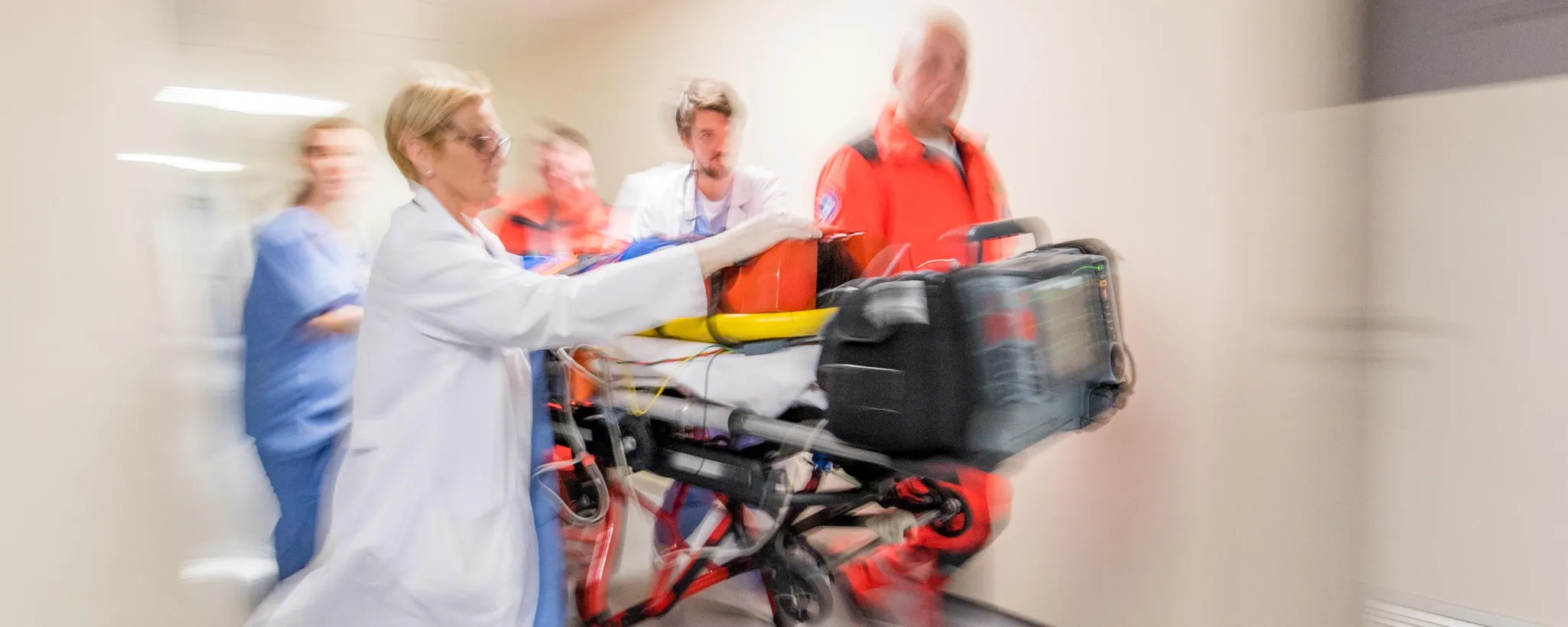 Notärzte bei der Arbeit schieben eine Trage mit einem Patienten durch einen Krankenhausflur