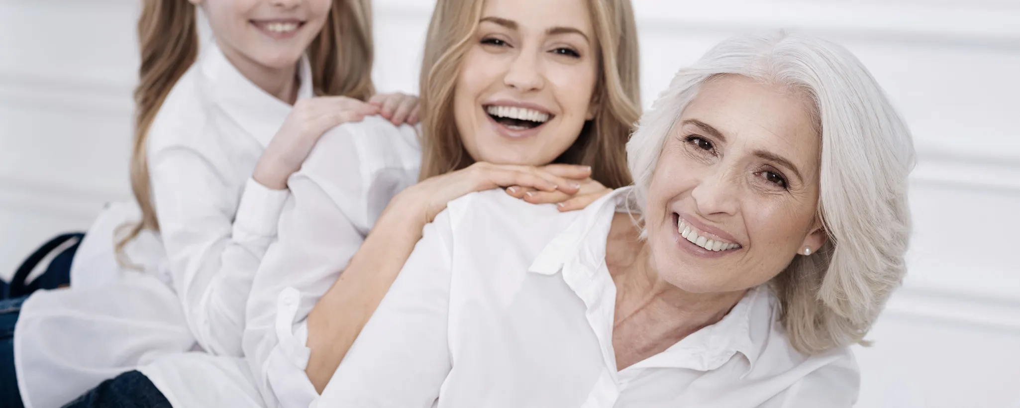 Drei Generationen liegen entspannt aufeinander, alle in weißen Hemden gekleidet. Sie genießen die gemeinsame Zeit, während die Erbschaftssteuer in Gesprächen möglicherweise eine Rolle spielt.