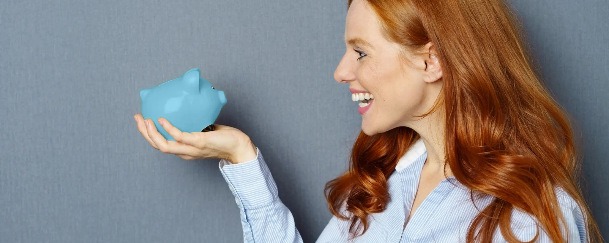 Eine Person hält eine blaue Sparschwein-Figur in der Hand. Das Bild symbolisiert finanzielle Sicherheit, wie sie durch eine Risikolebensversicherung gewährleistet wird. Es lädt dazu ein, über einen Test nachzudenken.